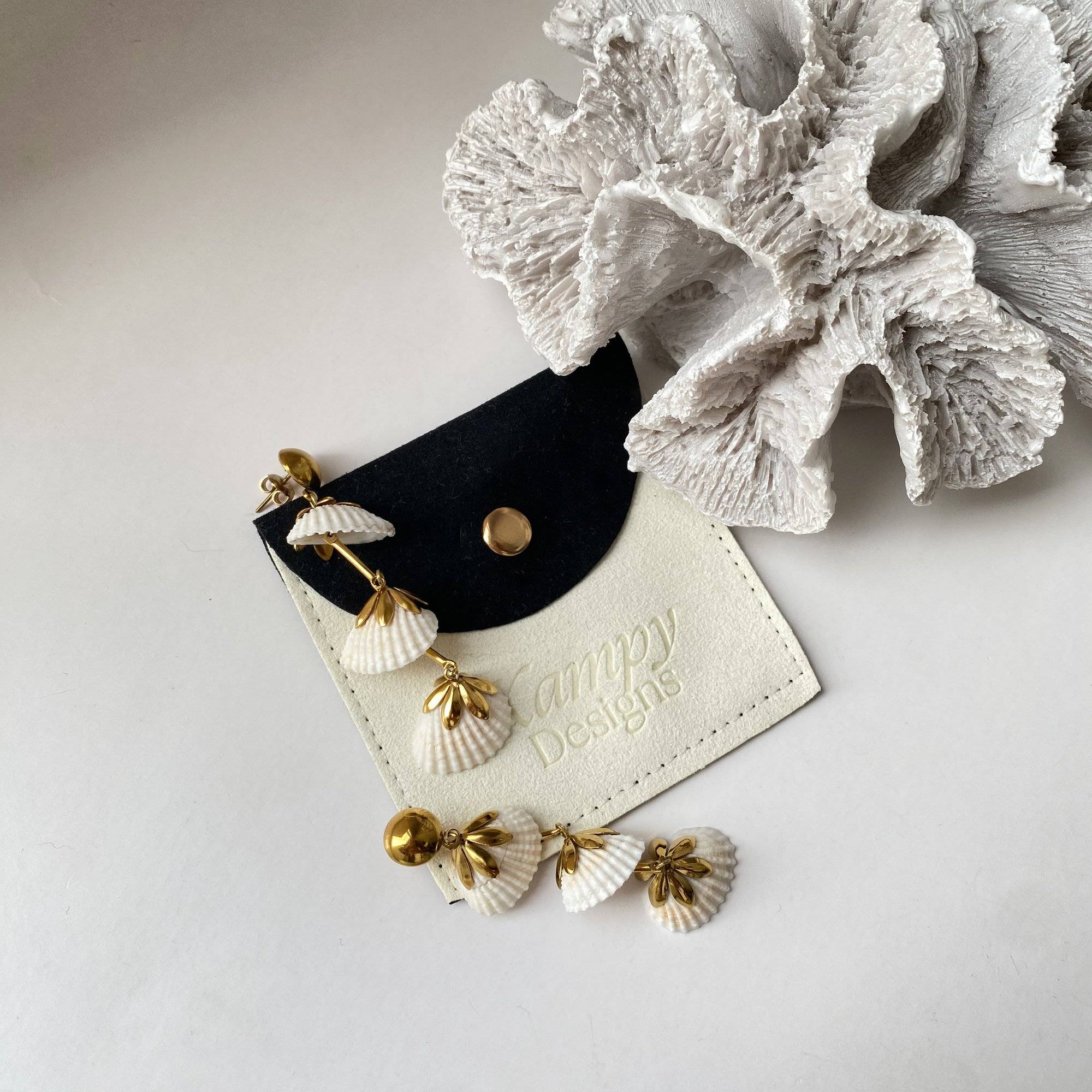 KlamidyaE real shell dangle earrings by Kampy Designs styled in a flat lay with coral decor, emphasizing their natural beach aesthetic.