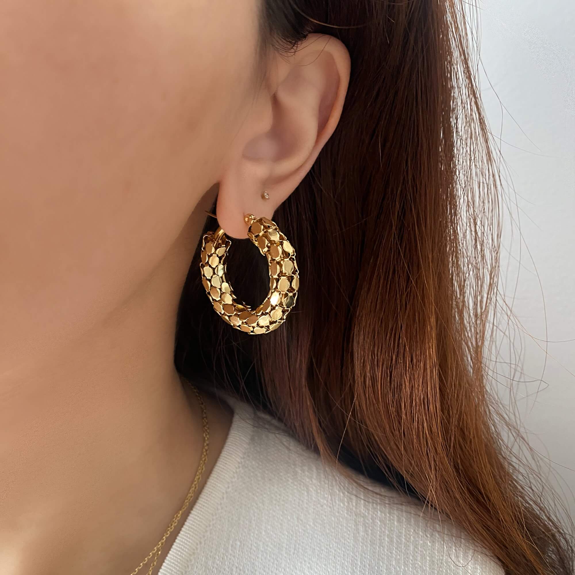 Kassiane serpentine scale hoop earrings by Kampy Designs, worn on model’s ear to highlight the textured serpent-inspired pattern and curved silhouette.
