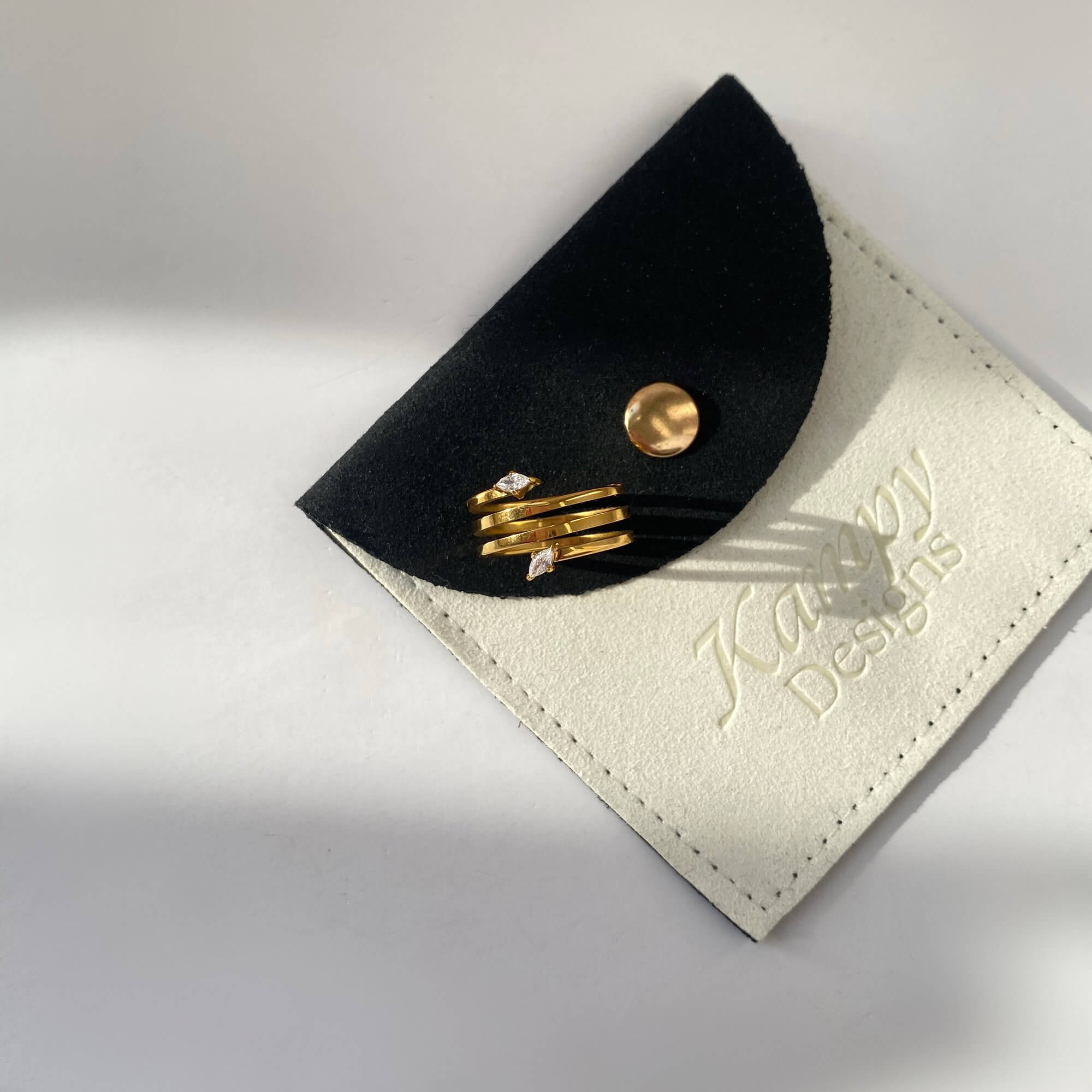 Top view of the Kinor serpentine wrap ring by Kampy Designs, positioned on branded packaging to emphasize product detail.