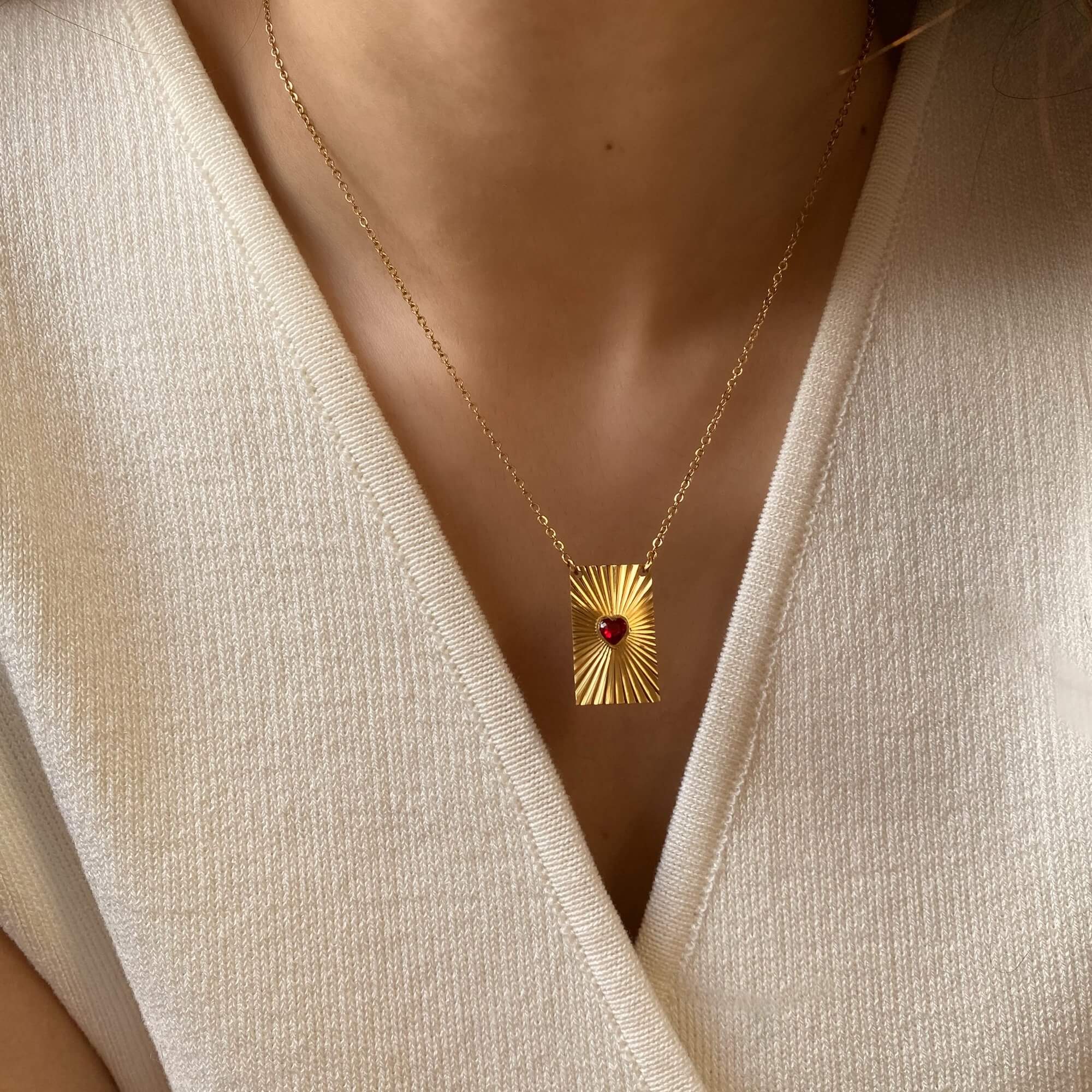 The KearyN sunburst rectangle heart pendant necklace by Kampy Designs, elegantly worn to showcase its striking pendant and delicate chain.
