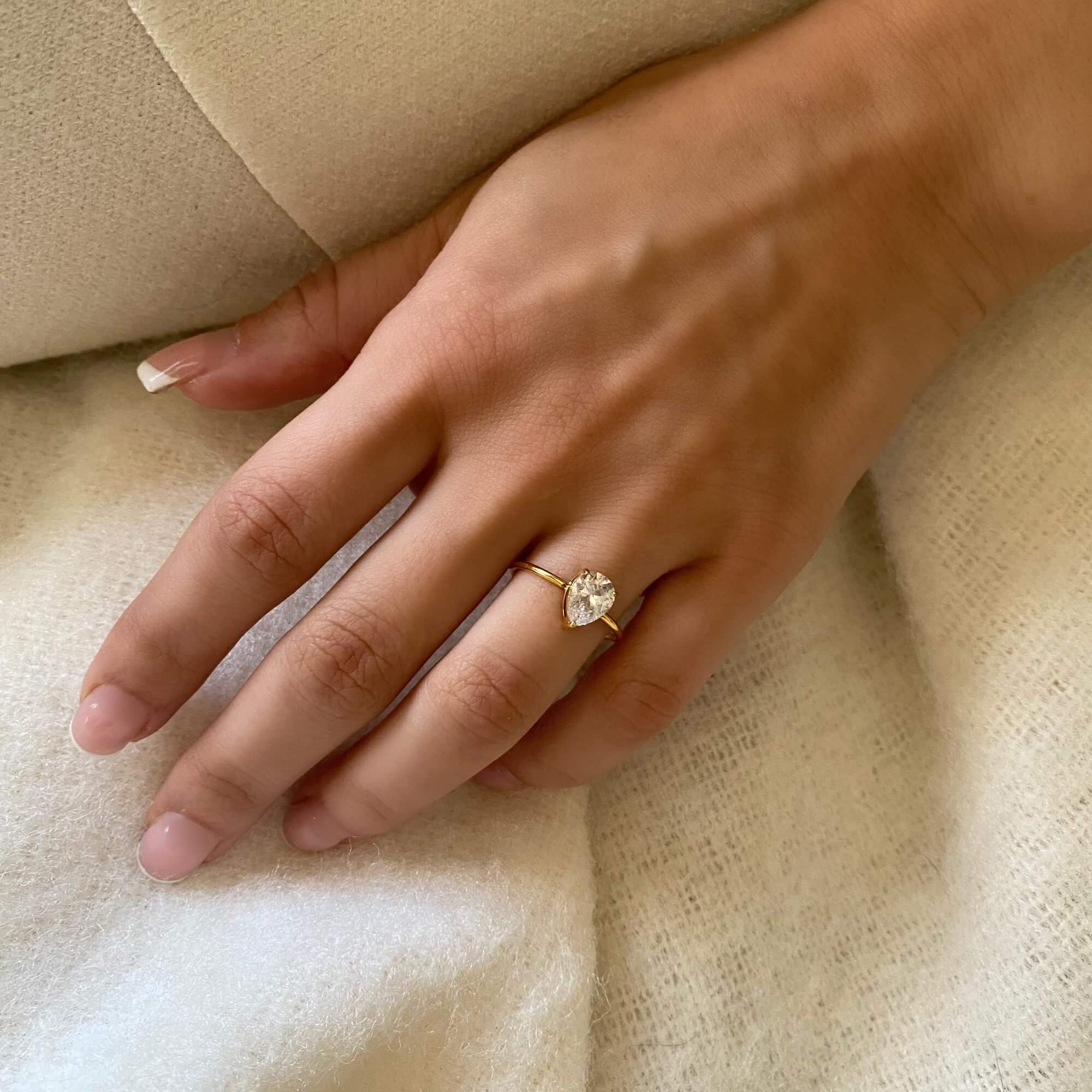 Angled view of the KateR thin band pear-cut diamond ring by Kampy Designs, showcasing its radiant pear-cut diamond and polished band.