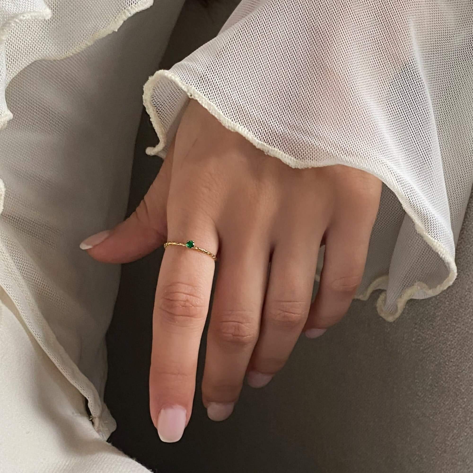 The KikoR thin diamond stacker ring by Kampy Designs, featuring a vibrant emerald gemstone set in a delicate gold band with shimmering diamonds.