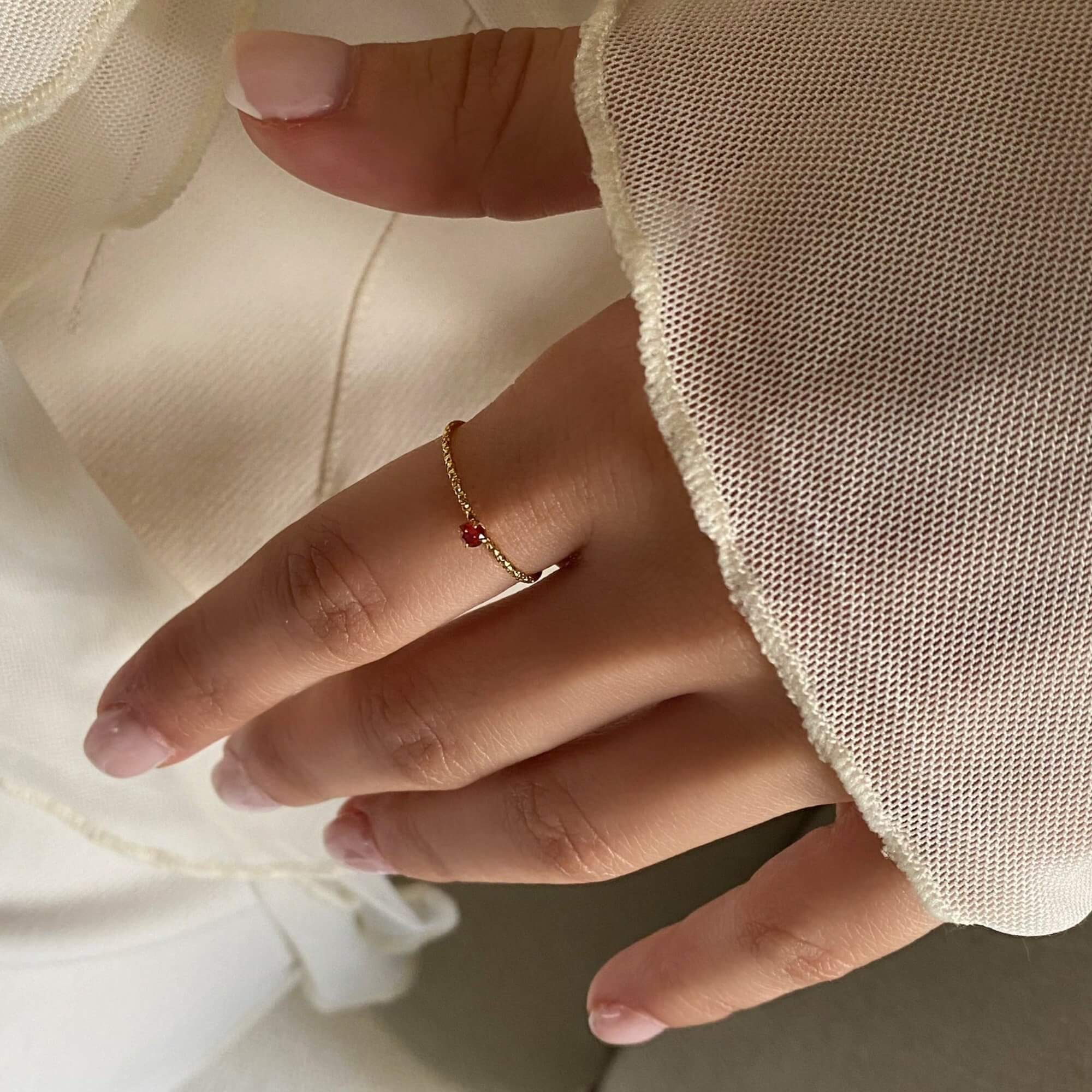 The KikoR thin diamond stacker ring by Kampy Designs, adorned with a stunning ruby gemstone and a delicate diamond-studded gold band.