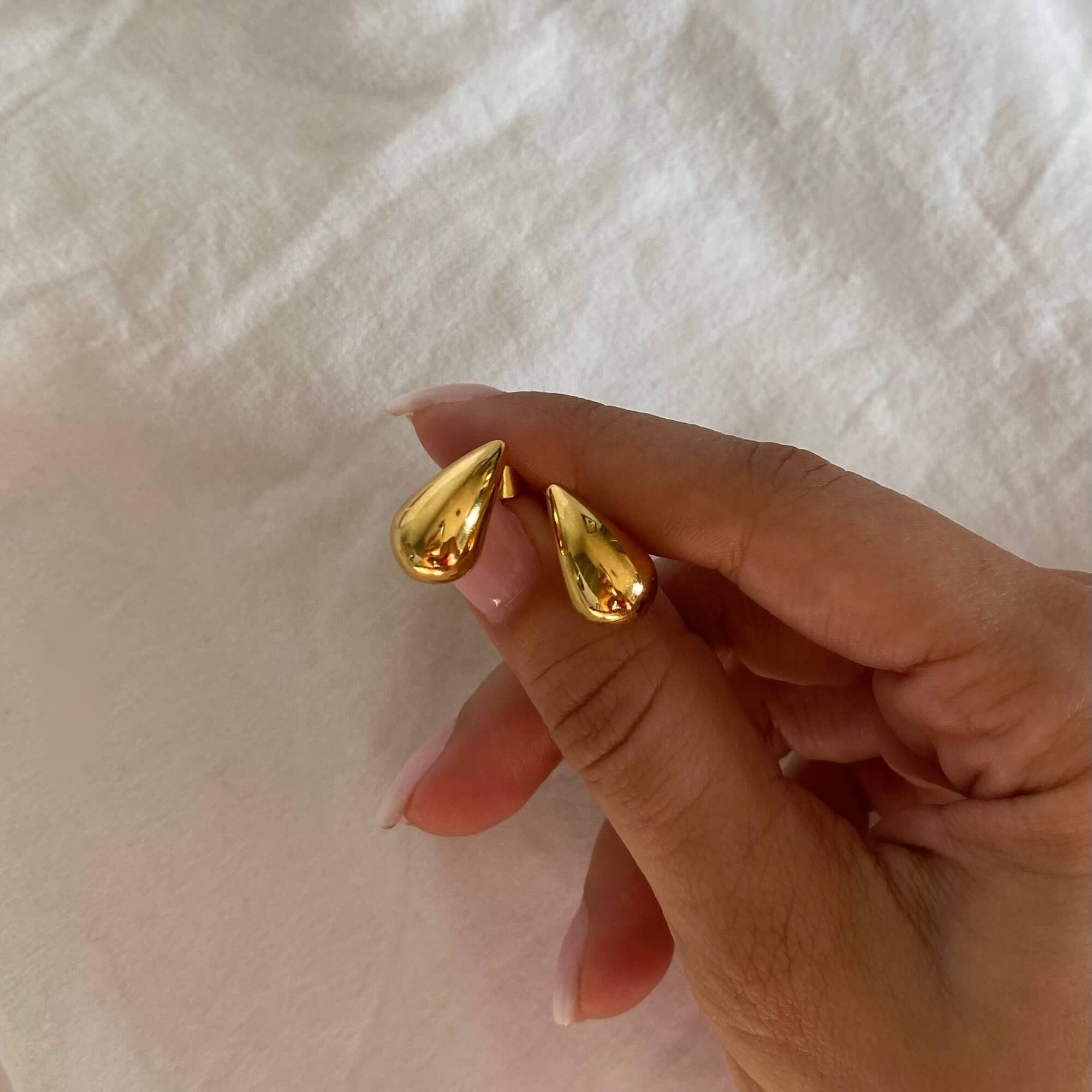 Front view of the KapreseE tiny gold tear drop earrings by Kampy Designs, showcasing their smooth and polished teardrop silhouette.