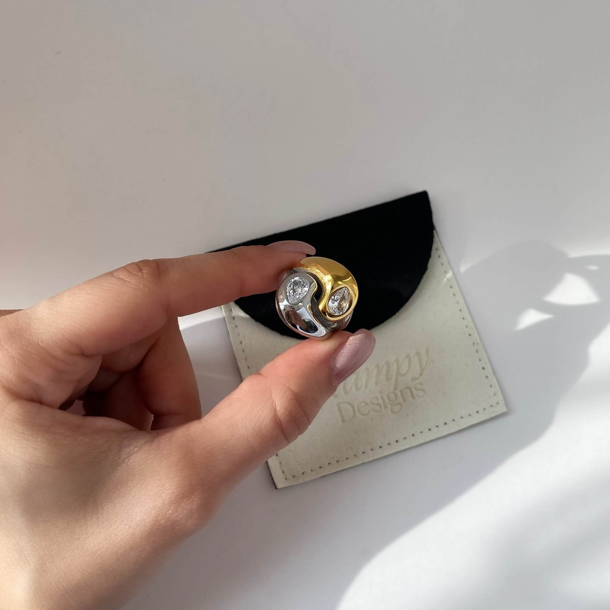 The KangR two-toned yin yang ring by Kampy Designs, held by model to capture its modern aesthetic and harmonious balance concept.