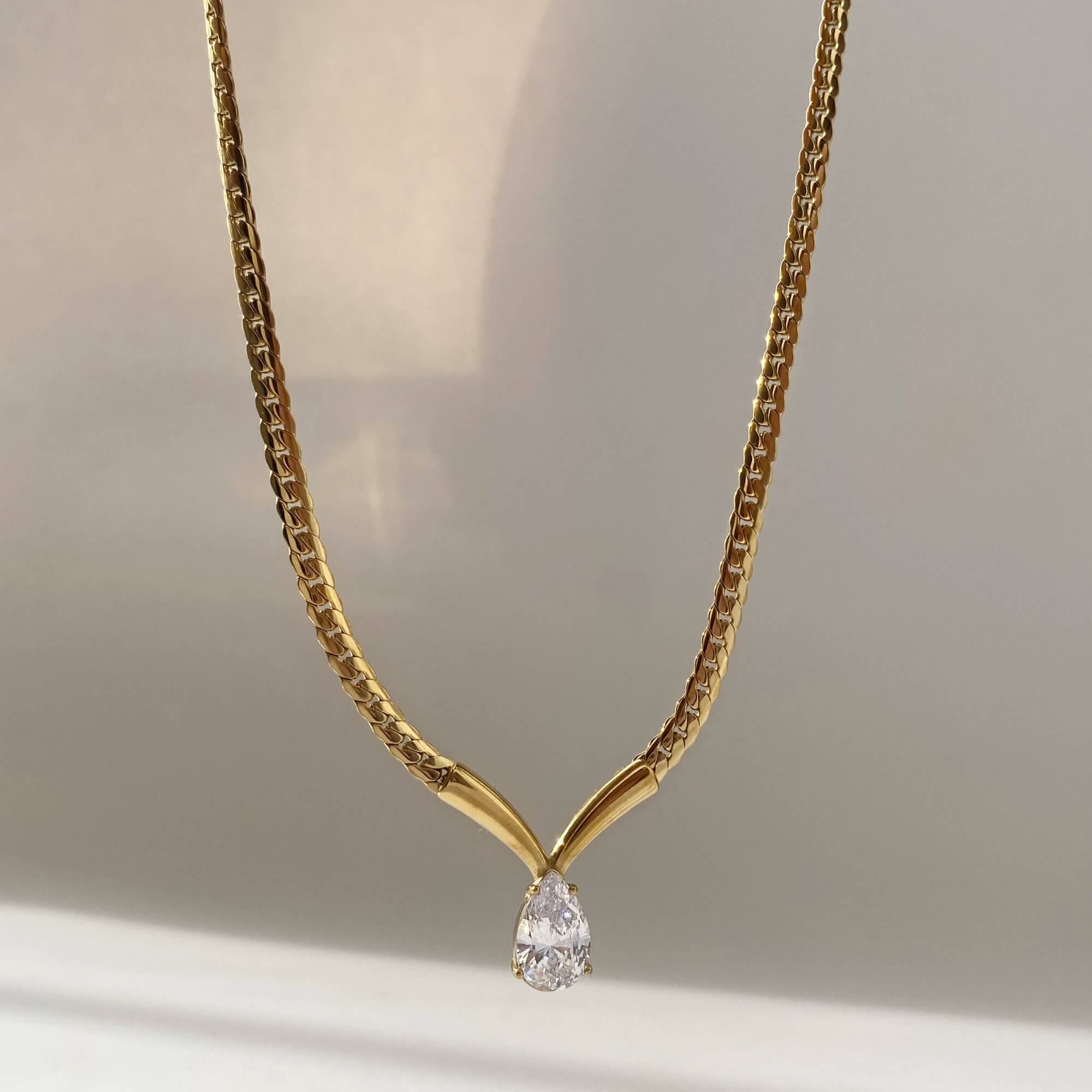 Close-up of the pear-shaped diamond on the Kaliyan V-chain necklace by Kampy Designs, highlighting the intricate setting and reflective shine.