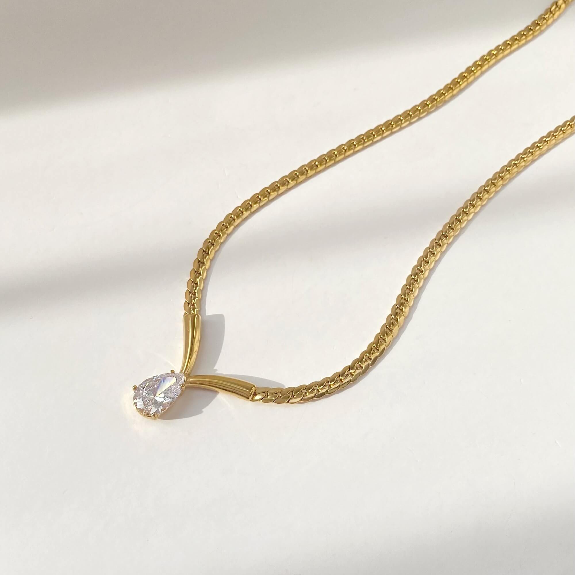 Flat lay of the Kaliyan V-chain necklace with pear-shaped diamond by Kampy Designs, displaying its fine craftsmanship and minimalist elegance.