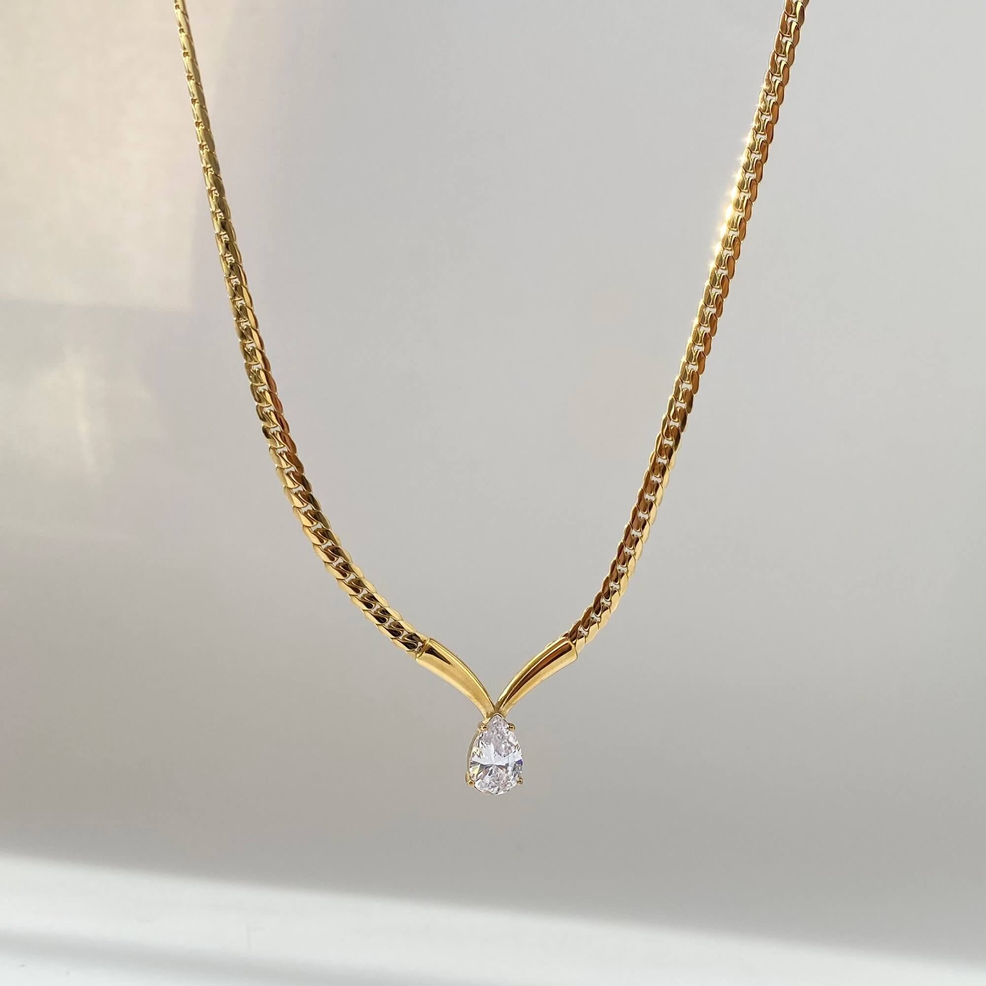 The Kaliyan V-chain necklace by Kampy Designs, shown hanging to highlight the pear-shaped diamond drop and fluid chain fall.