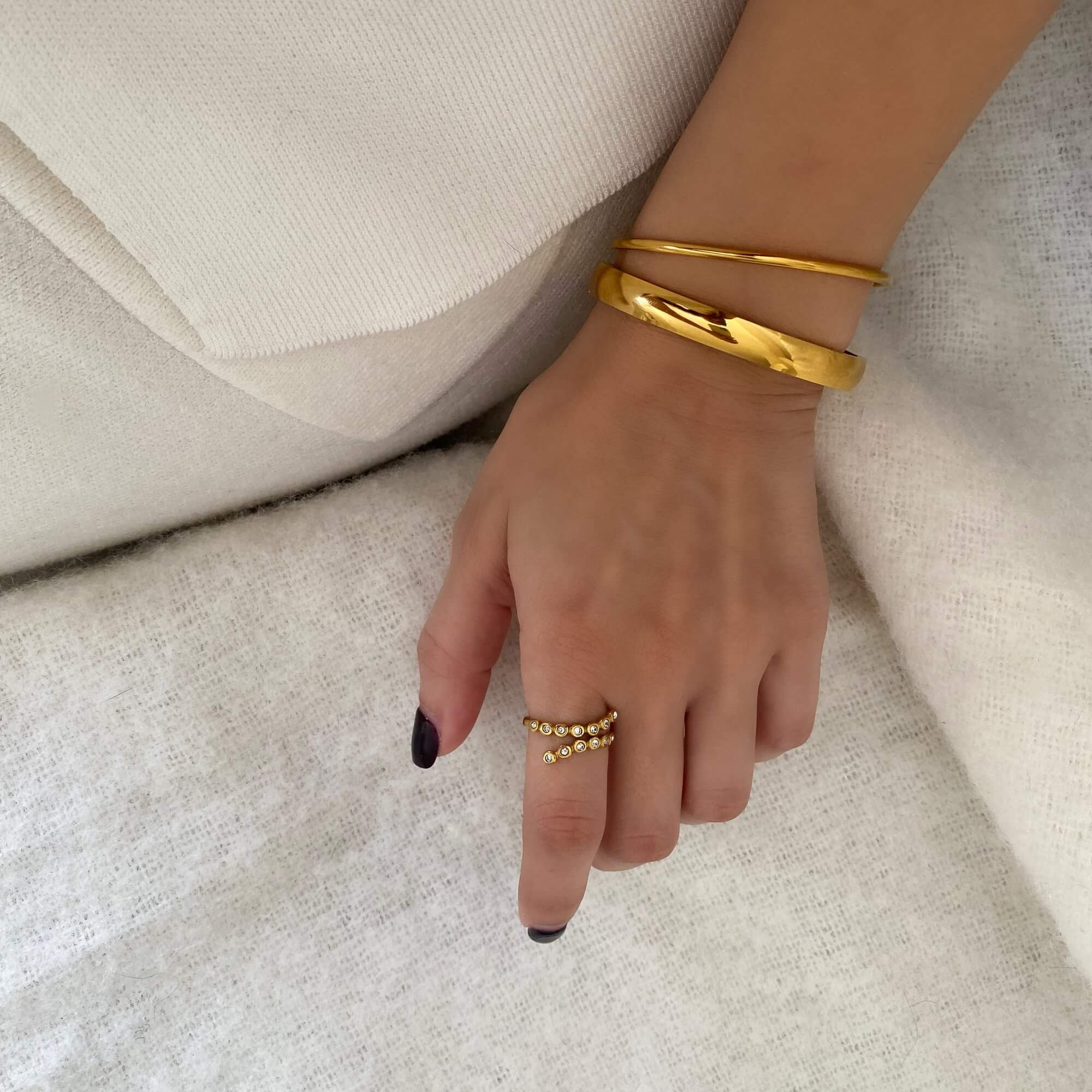 Angled view of the KazzyR zircon bezel wrap ring by Kampy Designs, highlighting the open band curve and bezel-set zircon from a dynamic angle.