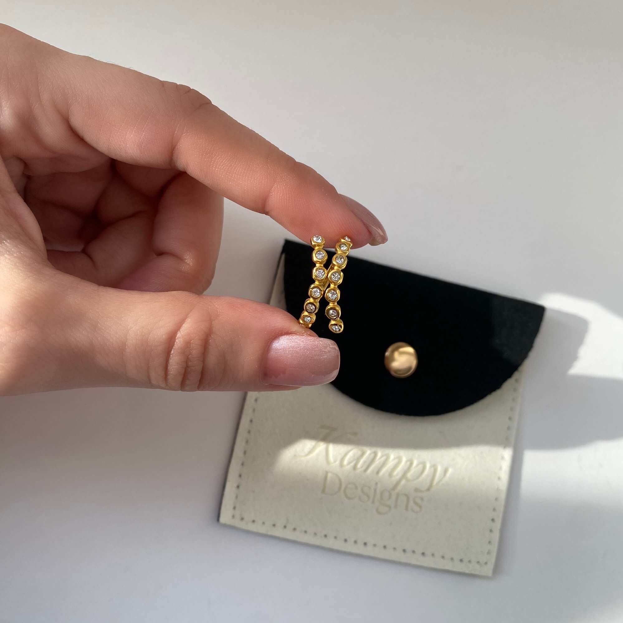 The KazzyR zircon bezel wrap ring by Kampy Designs, held by model to display its modern elegance and simplicity up close.