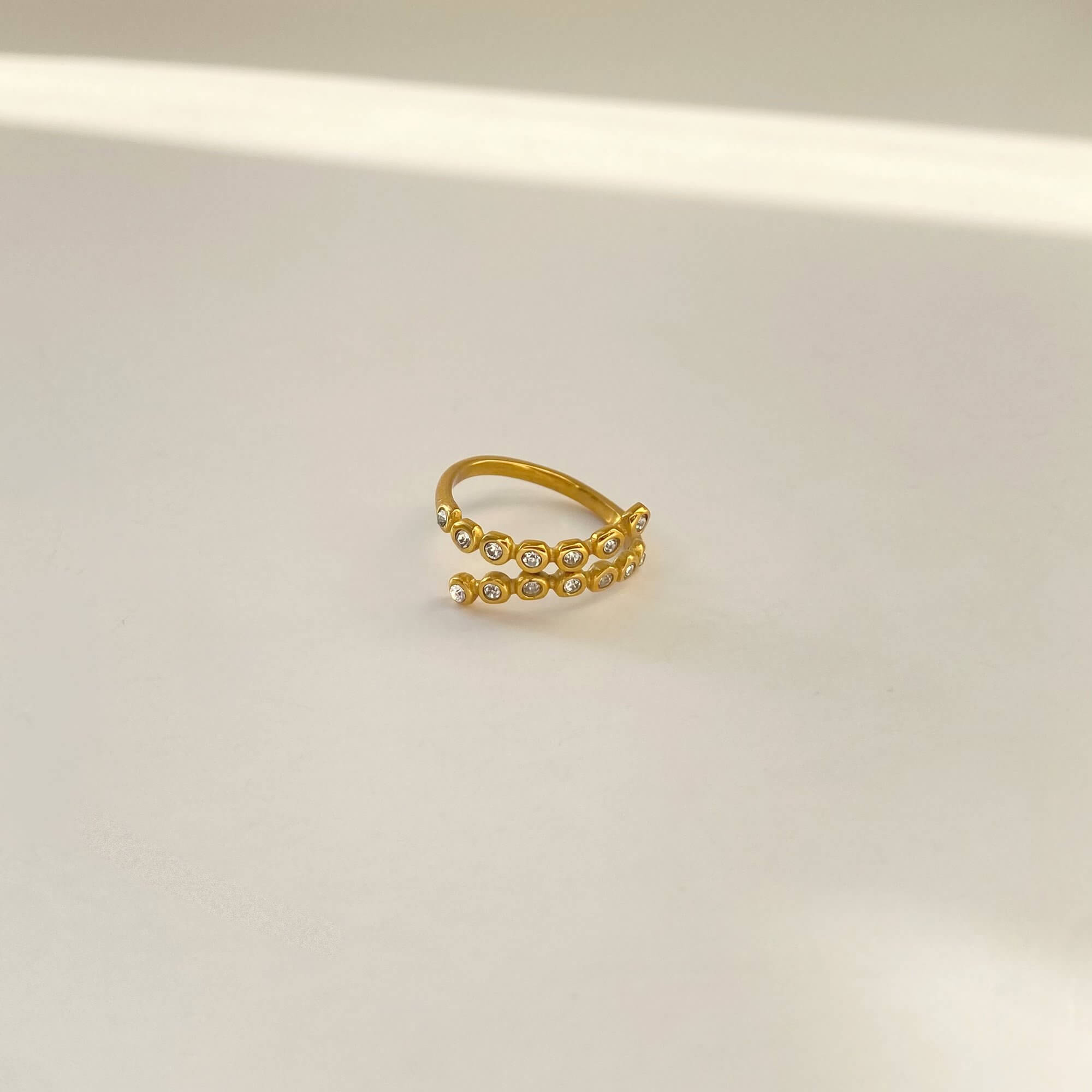 Flat lay of the KazzyR zircon bezel wrap ring by Kampy Designs, revealing its minimalistic and modern open wrap design
