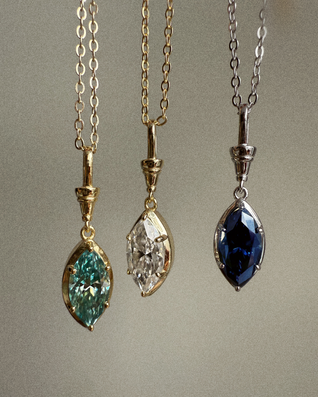 Marquise moissanite pendant necklaces showing green, white, and midnight blue stone color variations in gold and silver settings.