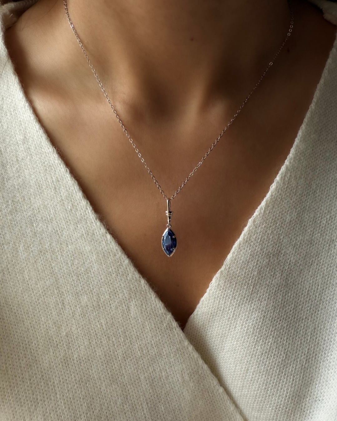 Midnight blue marquise moissanite pendant necklace worn on model with white gold-plated 925 sterling silver chain.