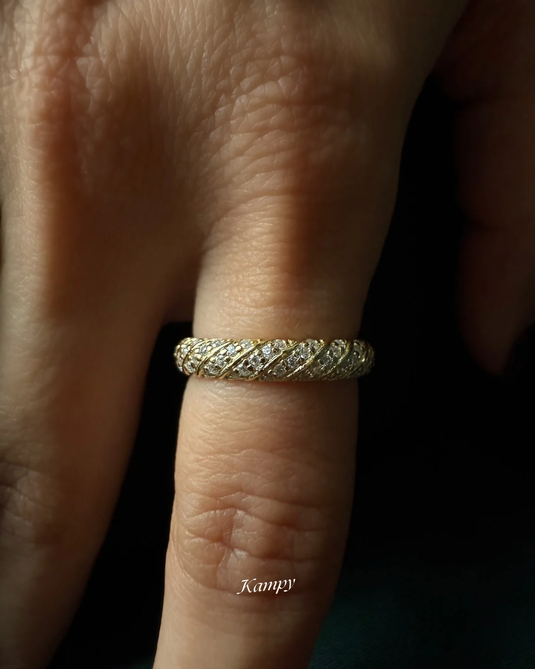 Macro close up detailed shot of the Luna Gold ring with pave moissanite accents on a finger, brand 'Kampy' visible.