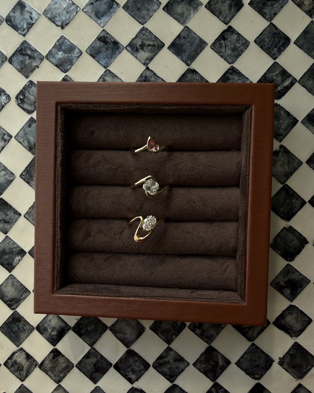 Asscher cut moissanite ring displayed in a jewelry tray alongside other sculptural rings