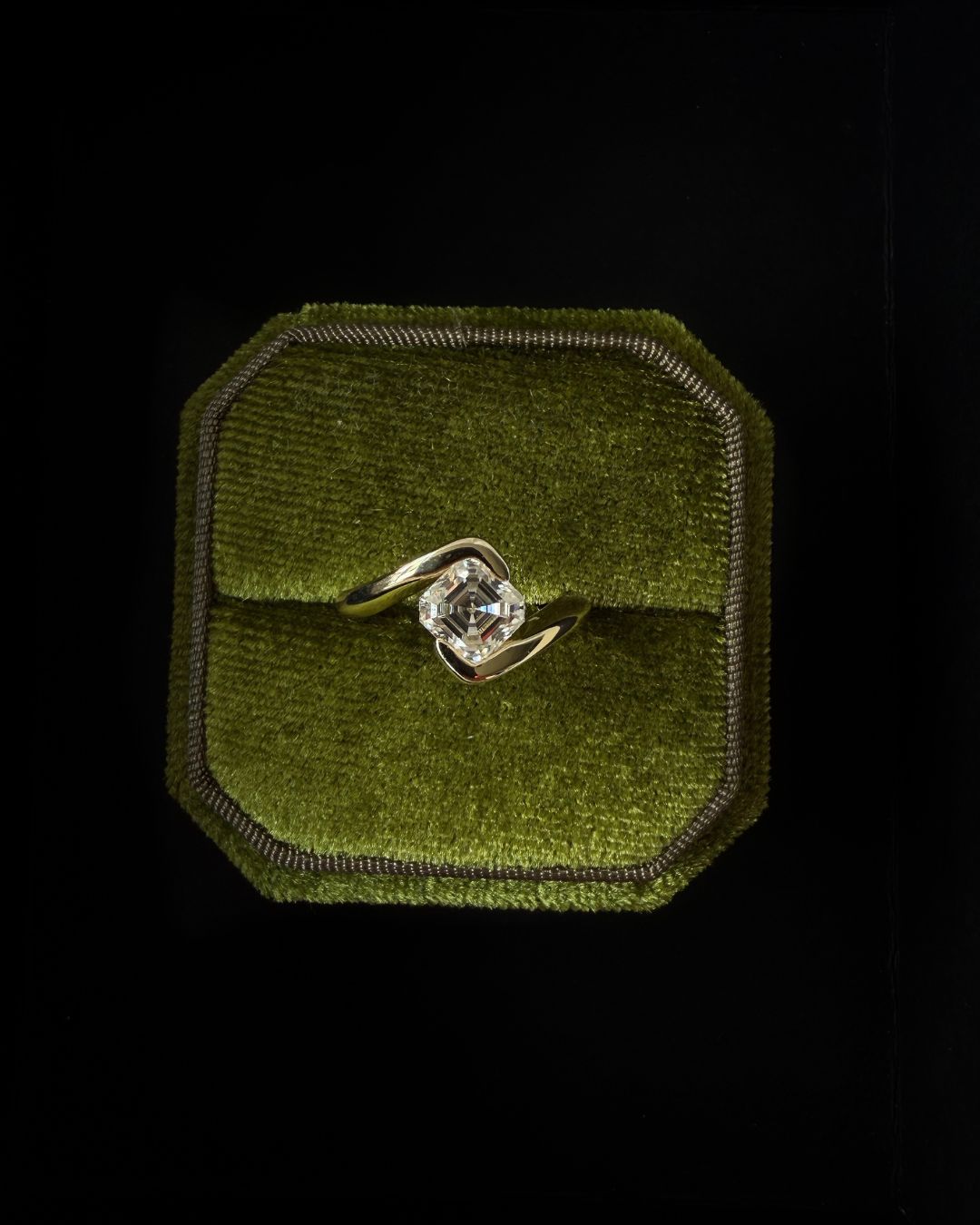 Asscher cut moissanite ring presented in a velvet jewelry box with a rich textured background