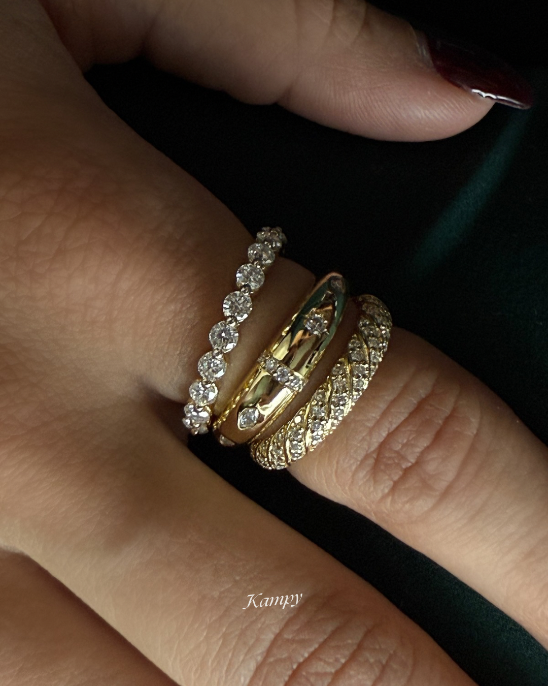Close-up of a hand wearing two gold rings with gemstones on a dark background