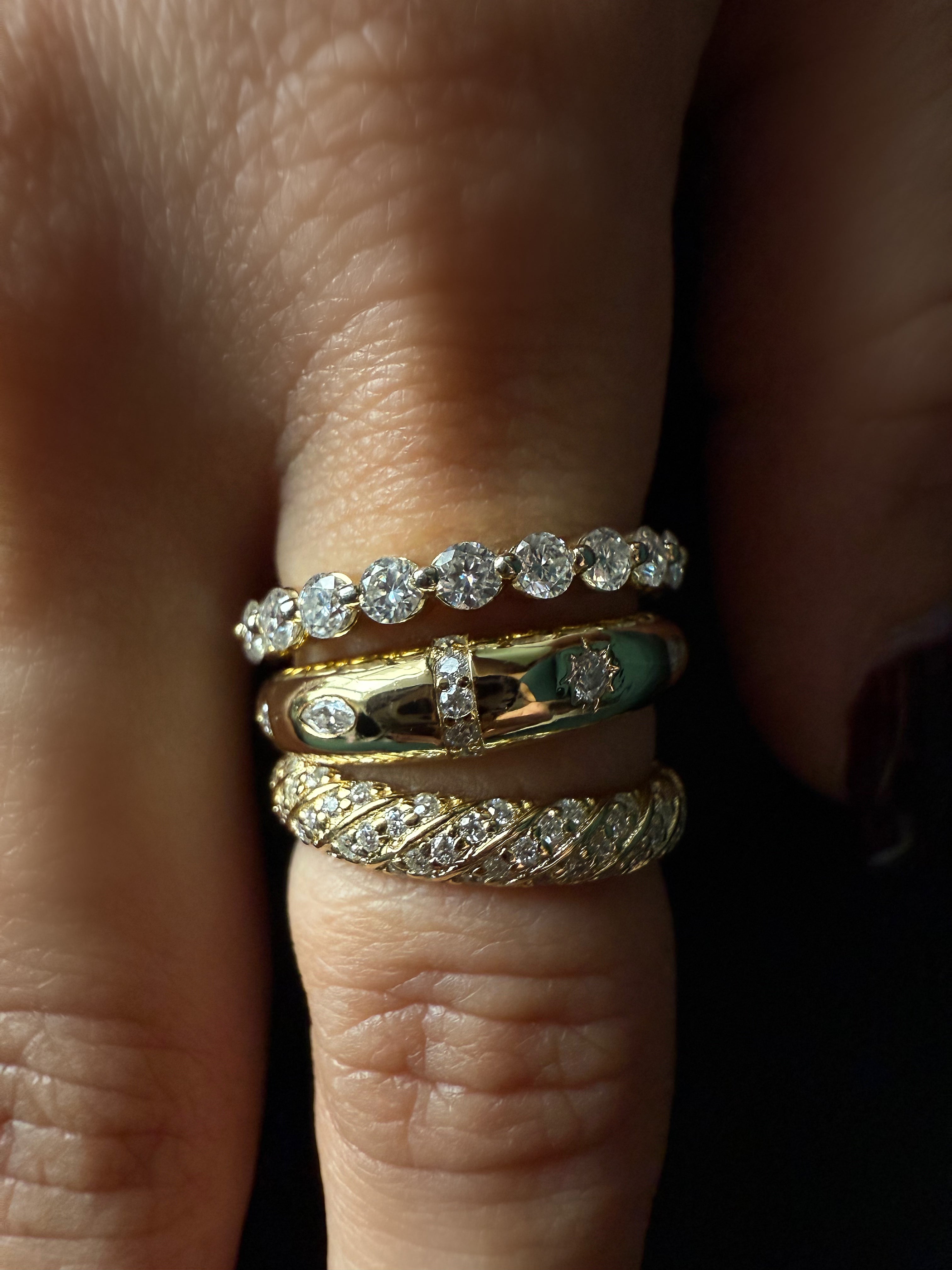 Close-up of a finger wearing multiple gold and diamond rings.