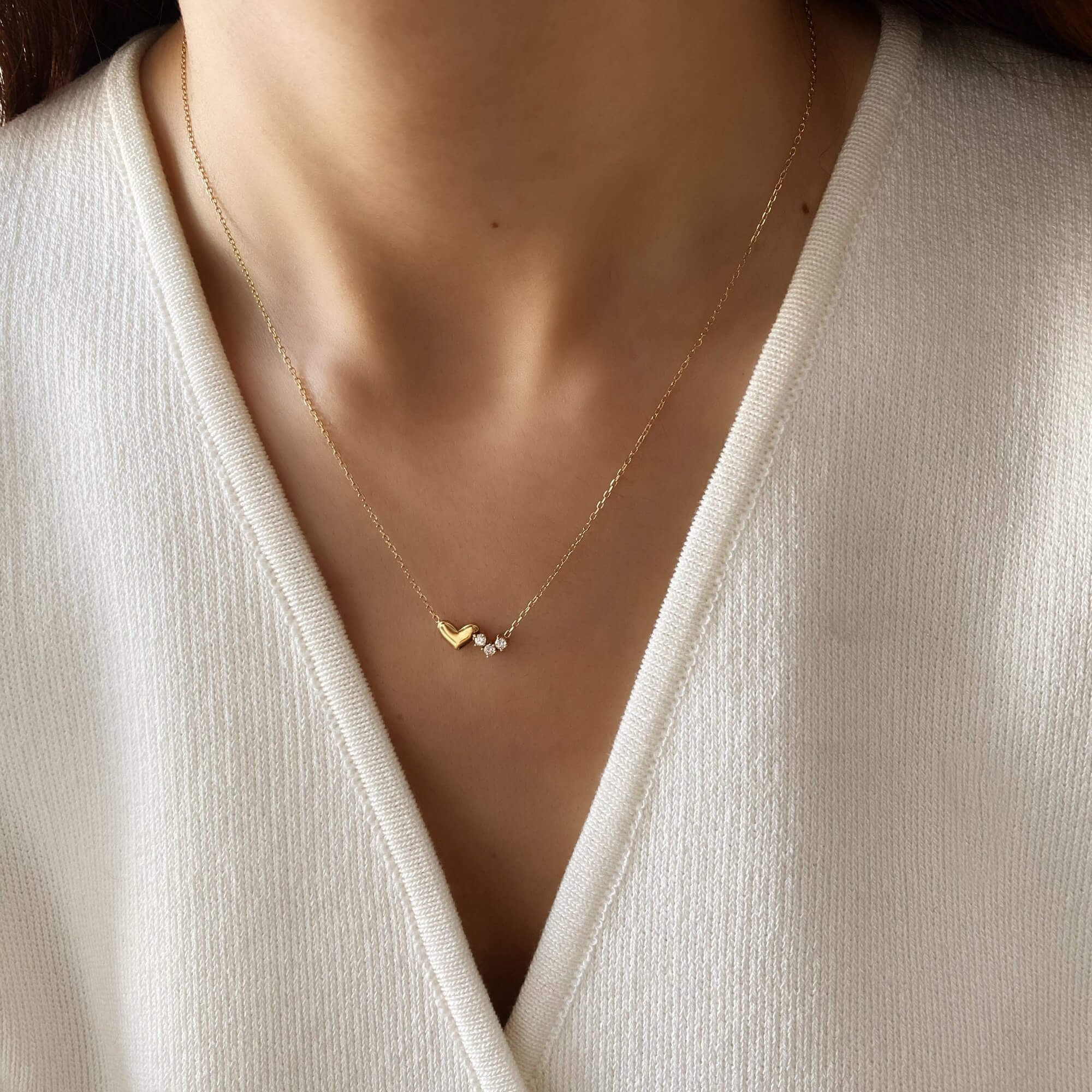 Close-up of the KassyN double heart charm necklace by Kampy Designs, worn to highlight its romantic intertwined heart design and elegant shine.