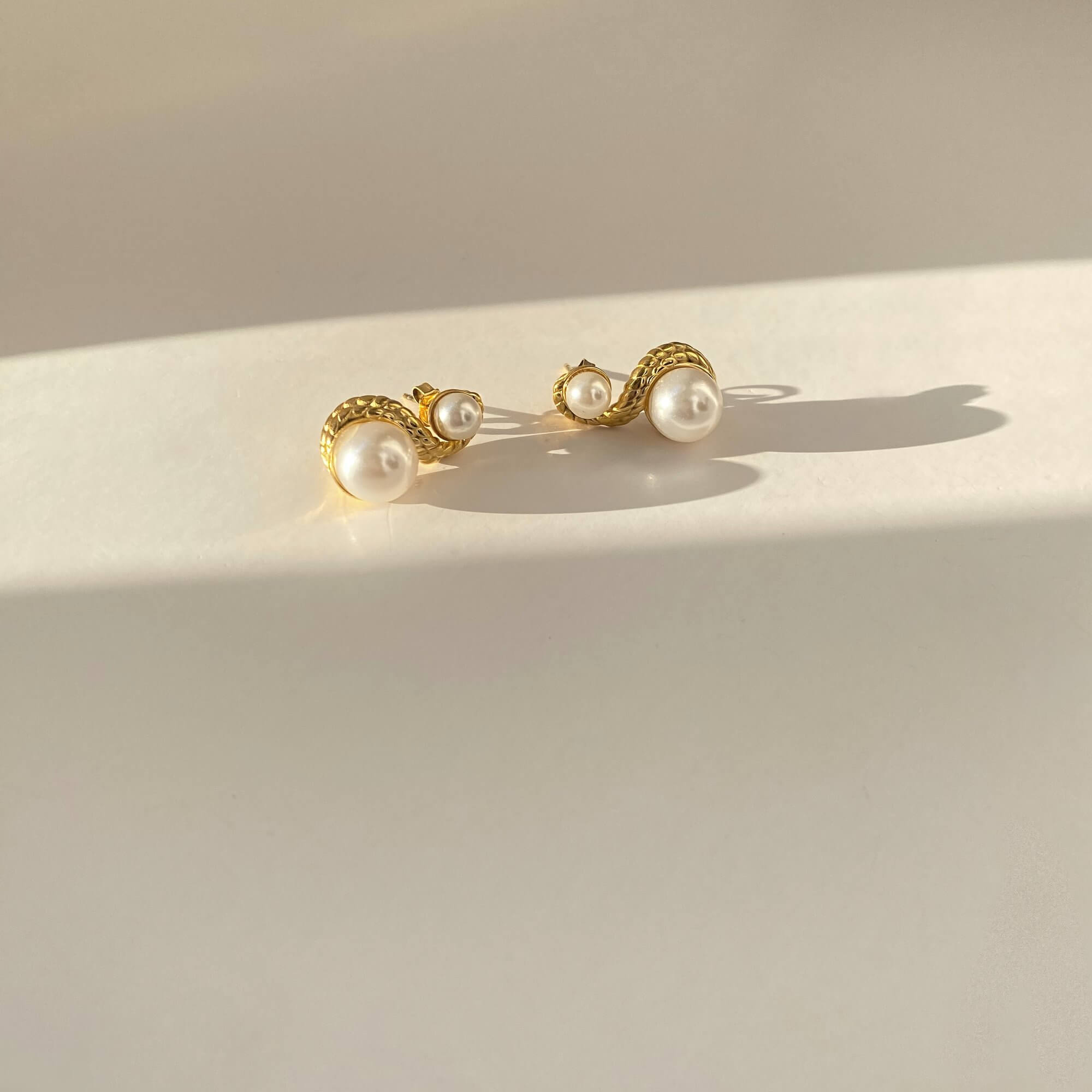 Angled flat lay of KaseyE double pearl drop earrings by Kampy Designs, showing the cascading design and soft sheen of each pearl.
