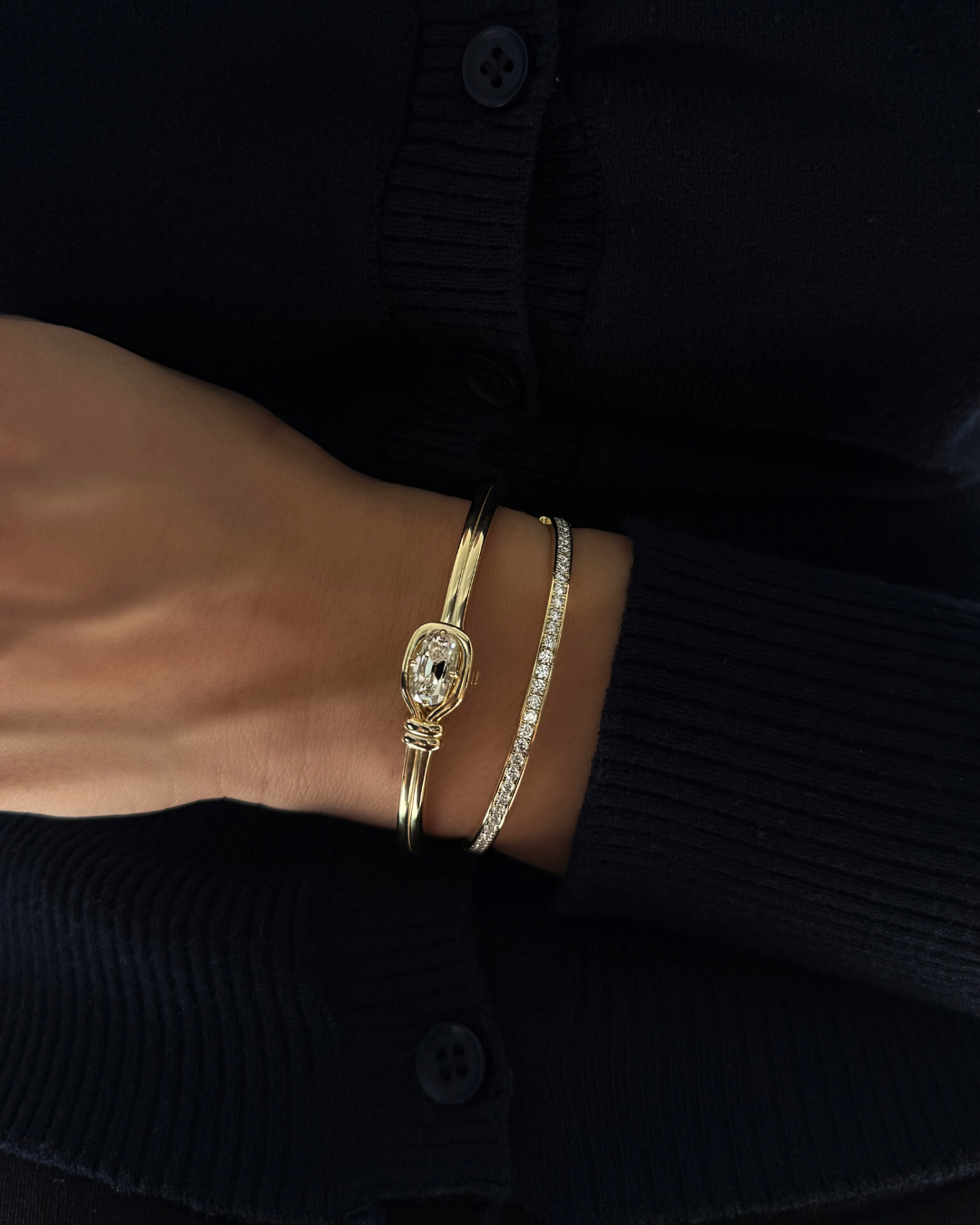 Stacked moissanite knot bangle and 2mm pavé tennis eternity bangle in 14K gold over sterling silver, modern layered bracelet styling.