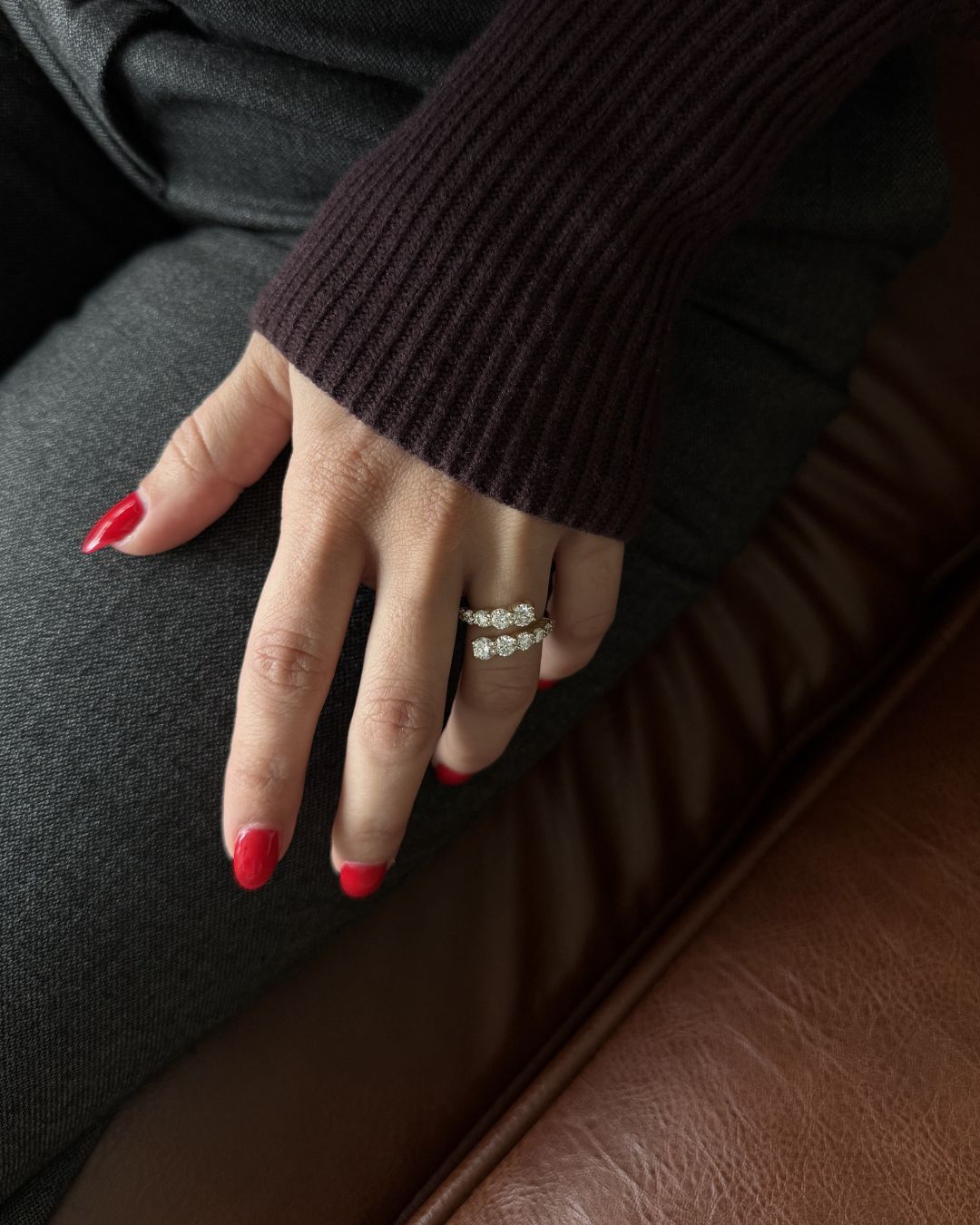 Gold moissanite open wrap statement ring worn on hand with neutral nails and burgundy knit styling.