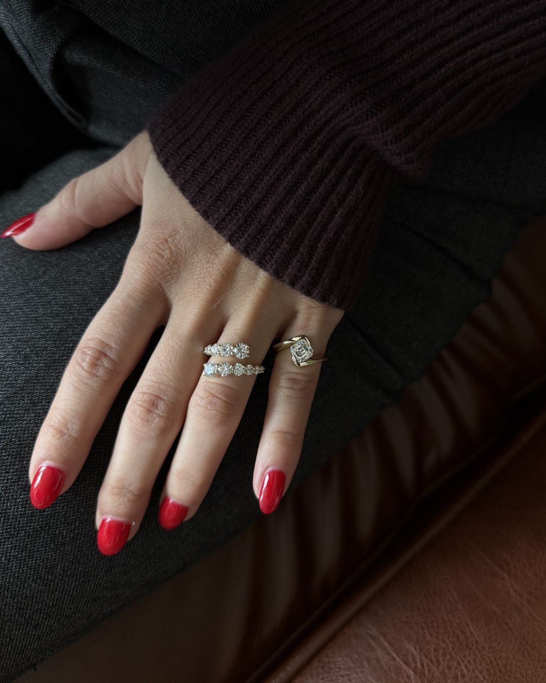 Gold moissanite open wrap ring styled as a pinky ring on a hand with red nails.