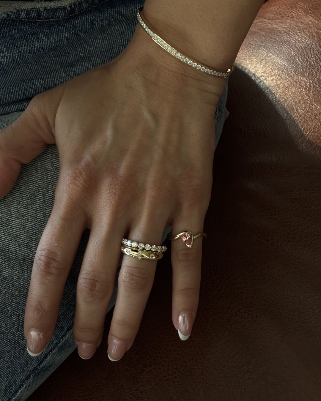 Gold pink gemstone pinky ring styled in a stacked ring look with complementary pieces
