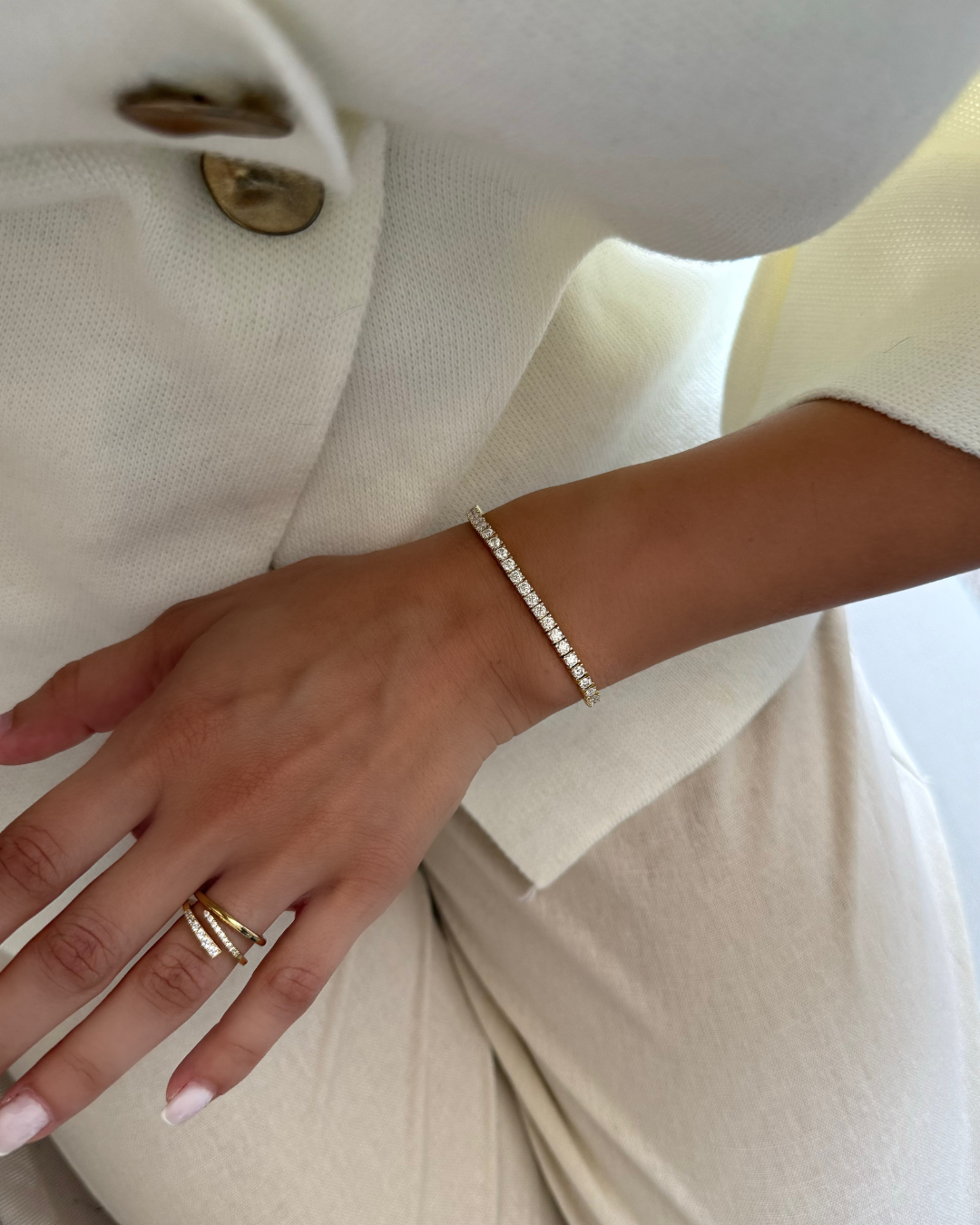 Close-up of a hand wearing a gold ring and silver bracelet on a white background