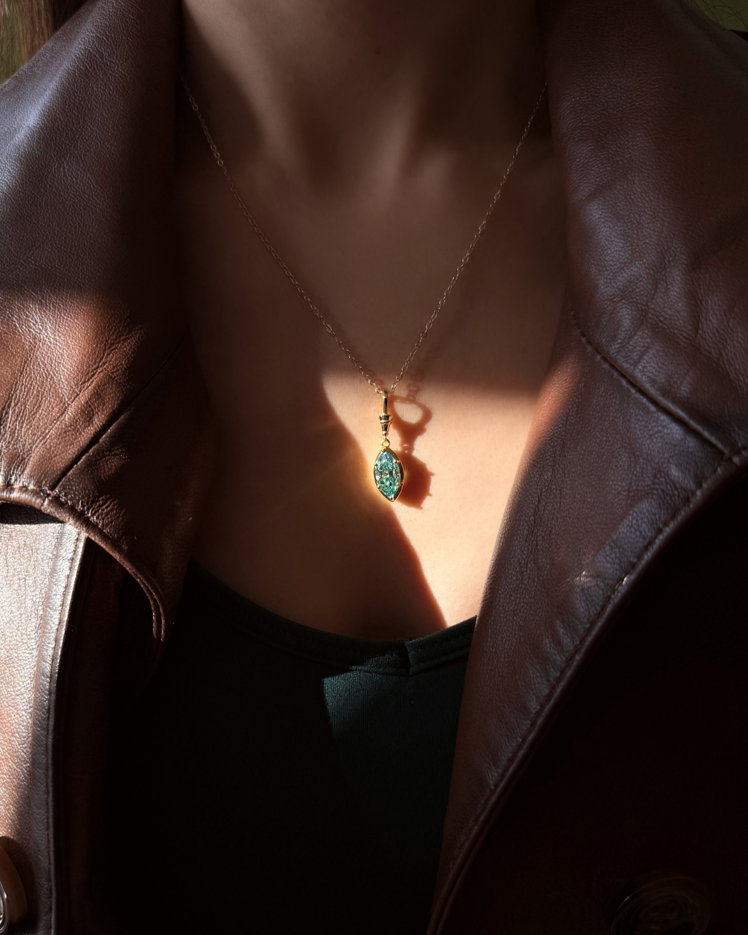 Green marquise-cut moissanite pendant necklace catching sunlight on model, gold chain, Kampy.
