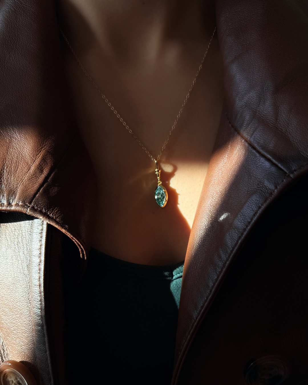 Green marquise moissanite pendant necklace with dramatic shadow lighting, gold chain, by Kampy.