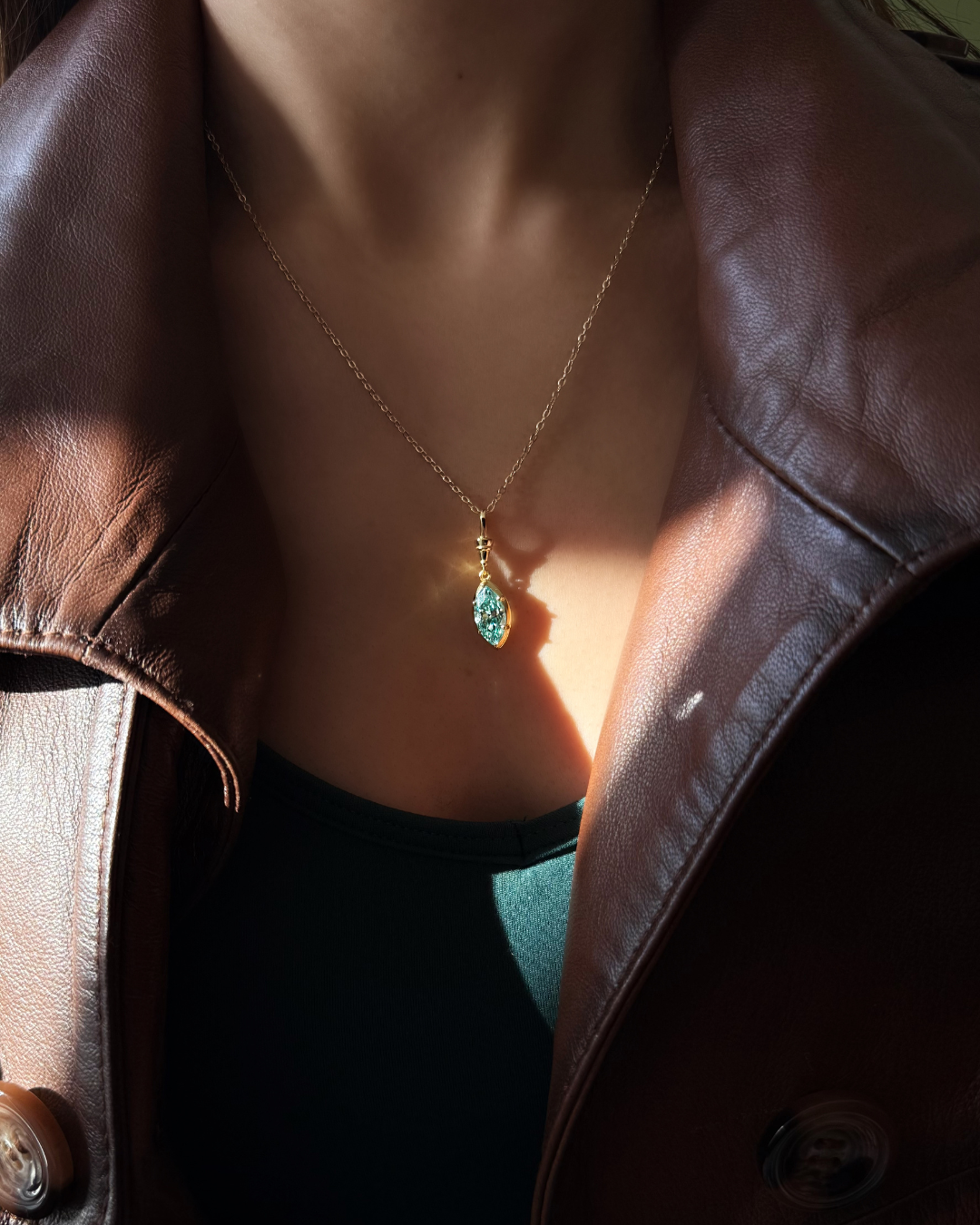 Close-up of green marquise moissanite pendant necklace in gold-plated 925 sterling silver worn on model by Kampy.