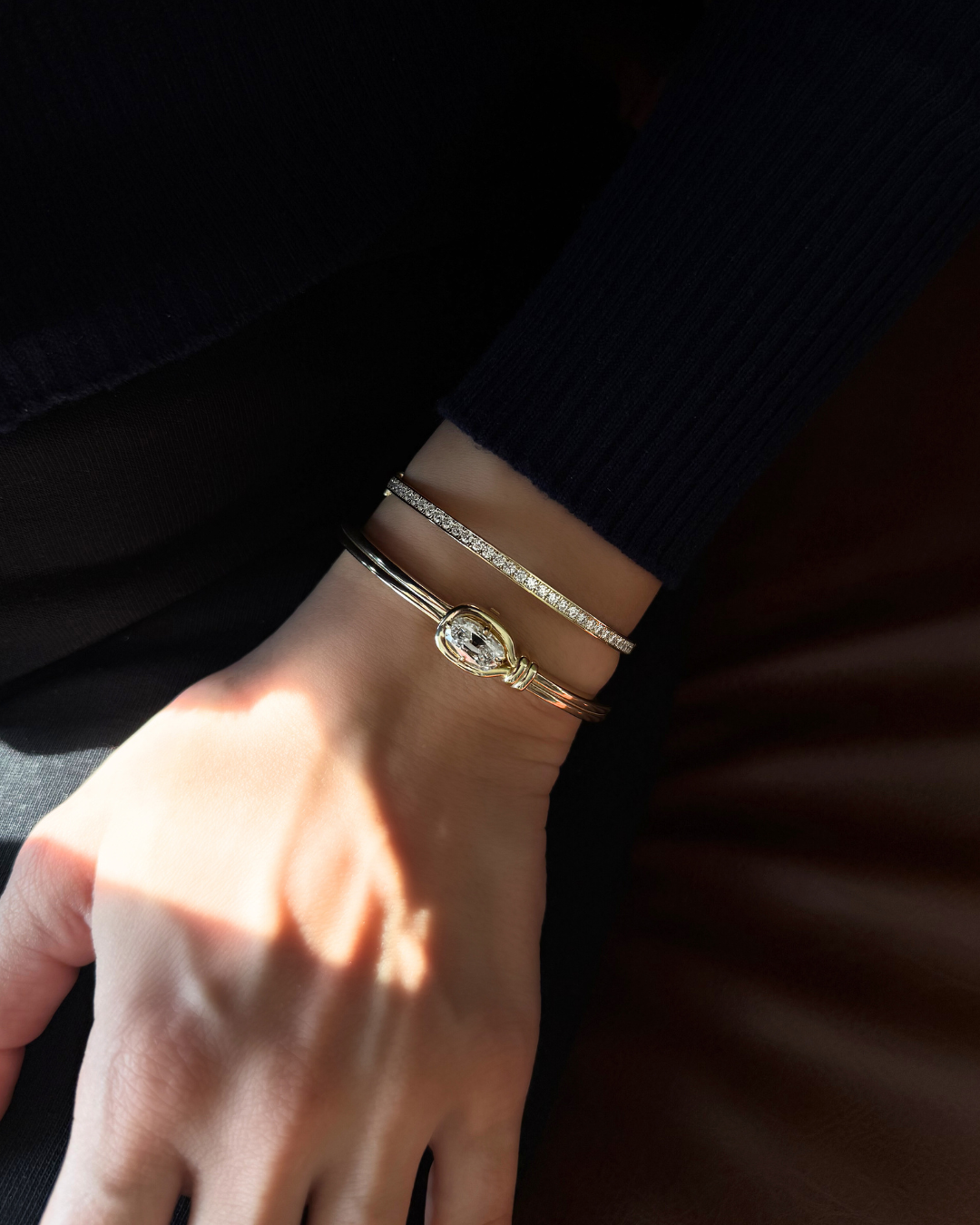 Lara moissanite tennis eternity bangle stacked with sculptural knot bangle in 14K gold over 925 sterling silver for modern layered styling.