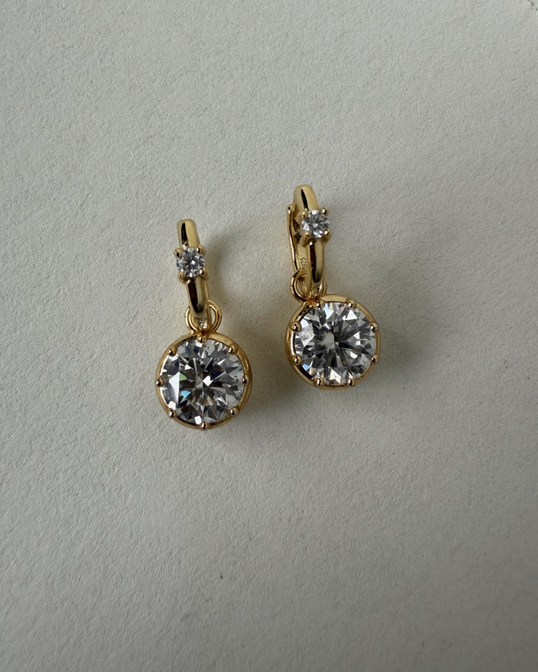 Kampy Designs Lumina Drop Earrings worn on ear, showcasing 2ct round-cut moissanite drop with gold huggie hoop.