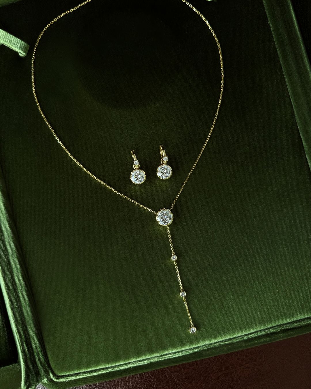 Lumina Drop Necklace and Lumina Drop Earrings styled together on a green jewelry box with matching round moissanite stones.