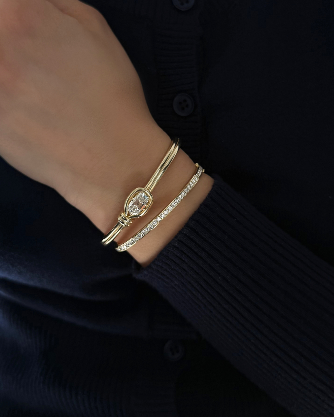 Lara moissanite tennis eternity bangle stacked with sculptural knot bangle in 14K gold over 925 sterling silver for modern layered styling.