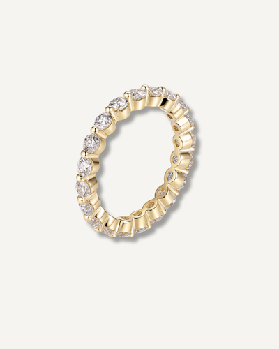 Round moissanite eternity band in gold finish on neutral background, Kampy Designs