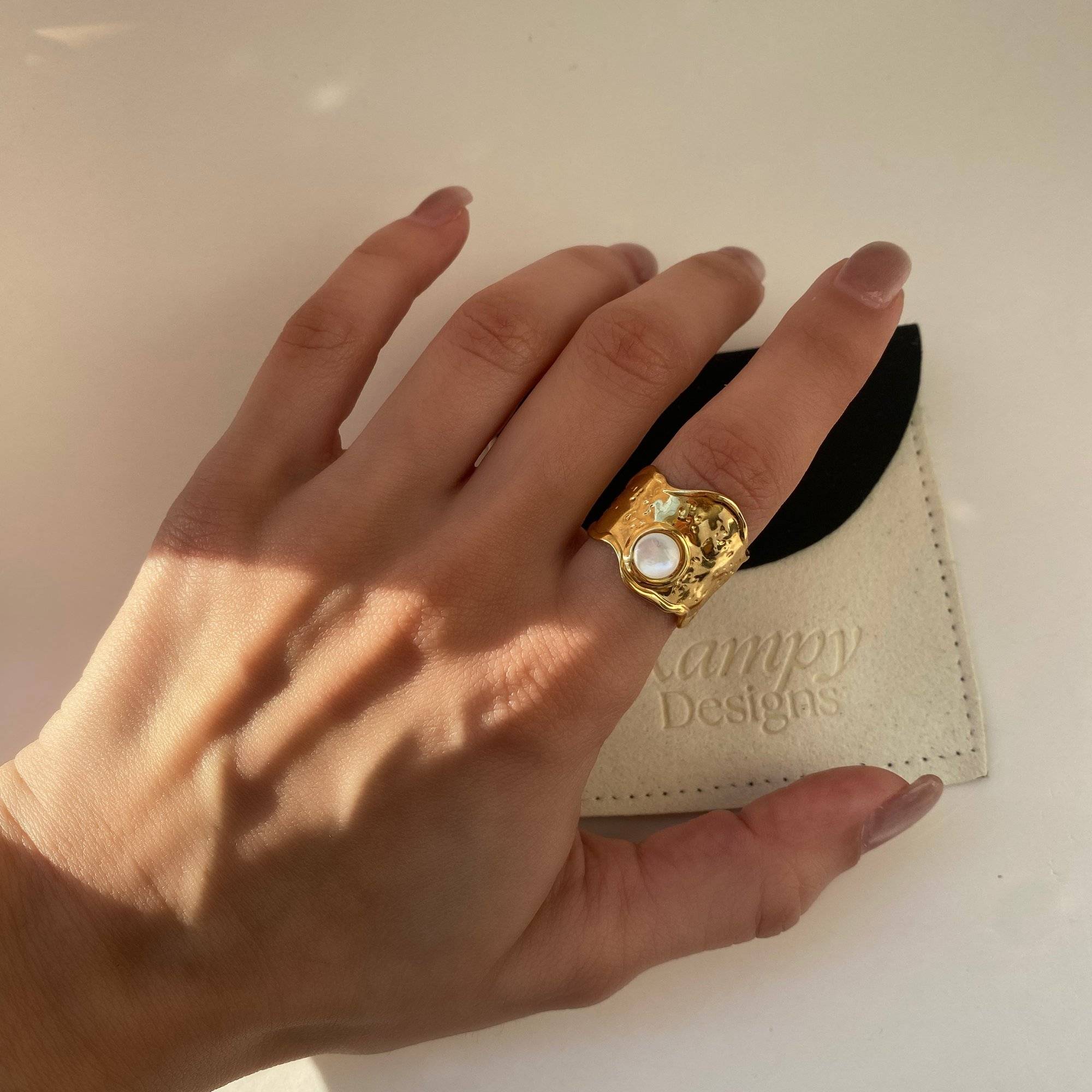 Top view of Kennar opal hammered ring by Kampy Designs, worn on model's finger to showcase the shimmering opal centerpiece and textured band.