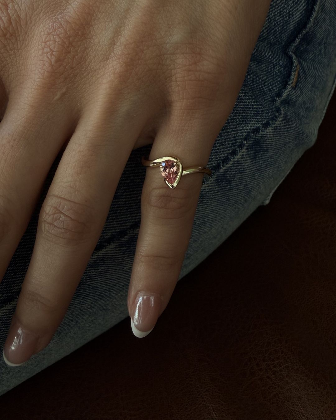 Pink sapphire pinky ring worn on hand with a minimal gold jewelry aesthetic