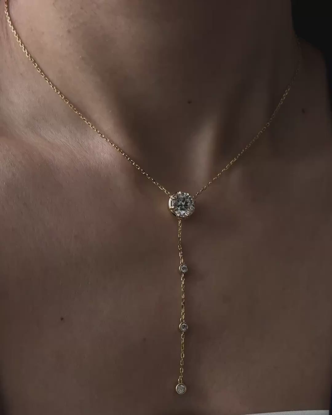 Model wearing the Lumina Drop Necklace by Kampy Designs, featuring a 3 ct round moissanite center stone and delicate gold lariat drop.