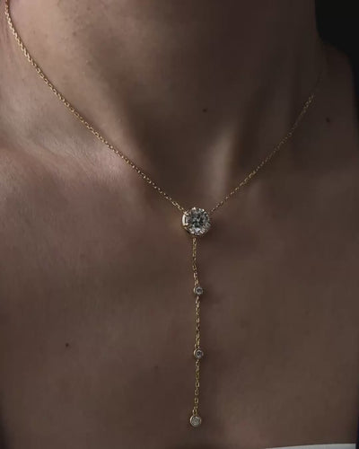 Model wearing the Lumina Drop Necklace by Kampy Designs, featuring a 3 ct round moissanite center stone and delicate gold lariat drop.