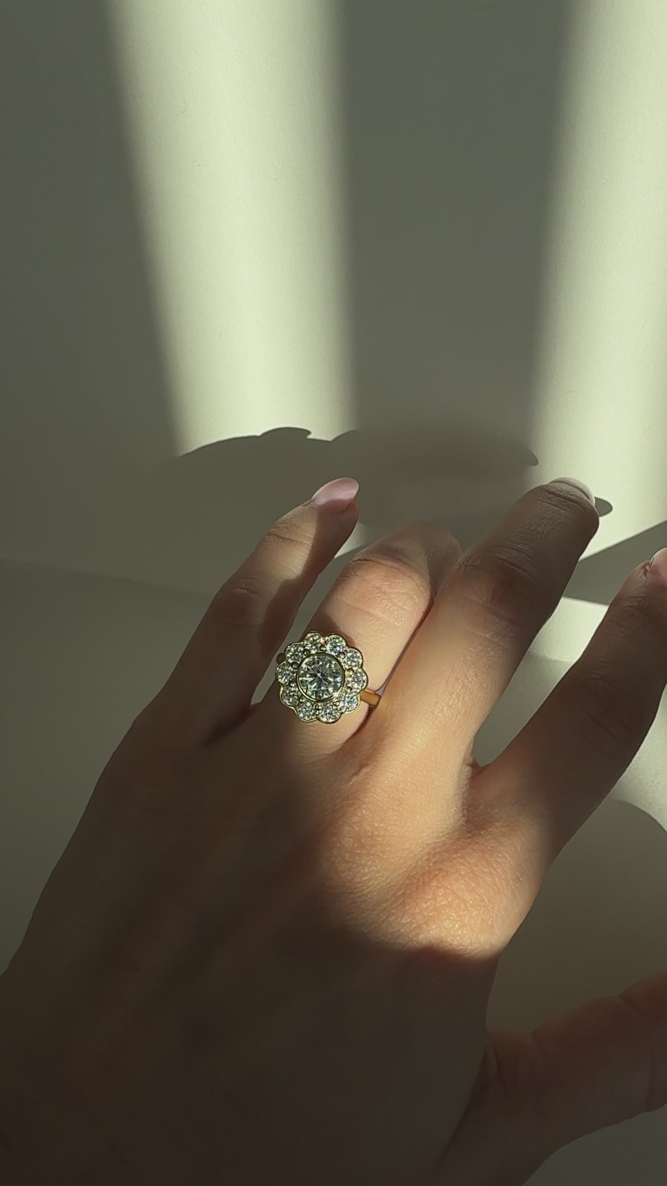 Close-up video of The Marigold Ring from Kampy Designs worn on a model’s finger, showing the sparkle of the 1ct center moissanite and floral halo stones in motion.
