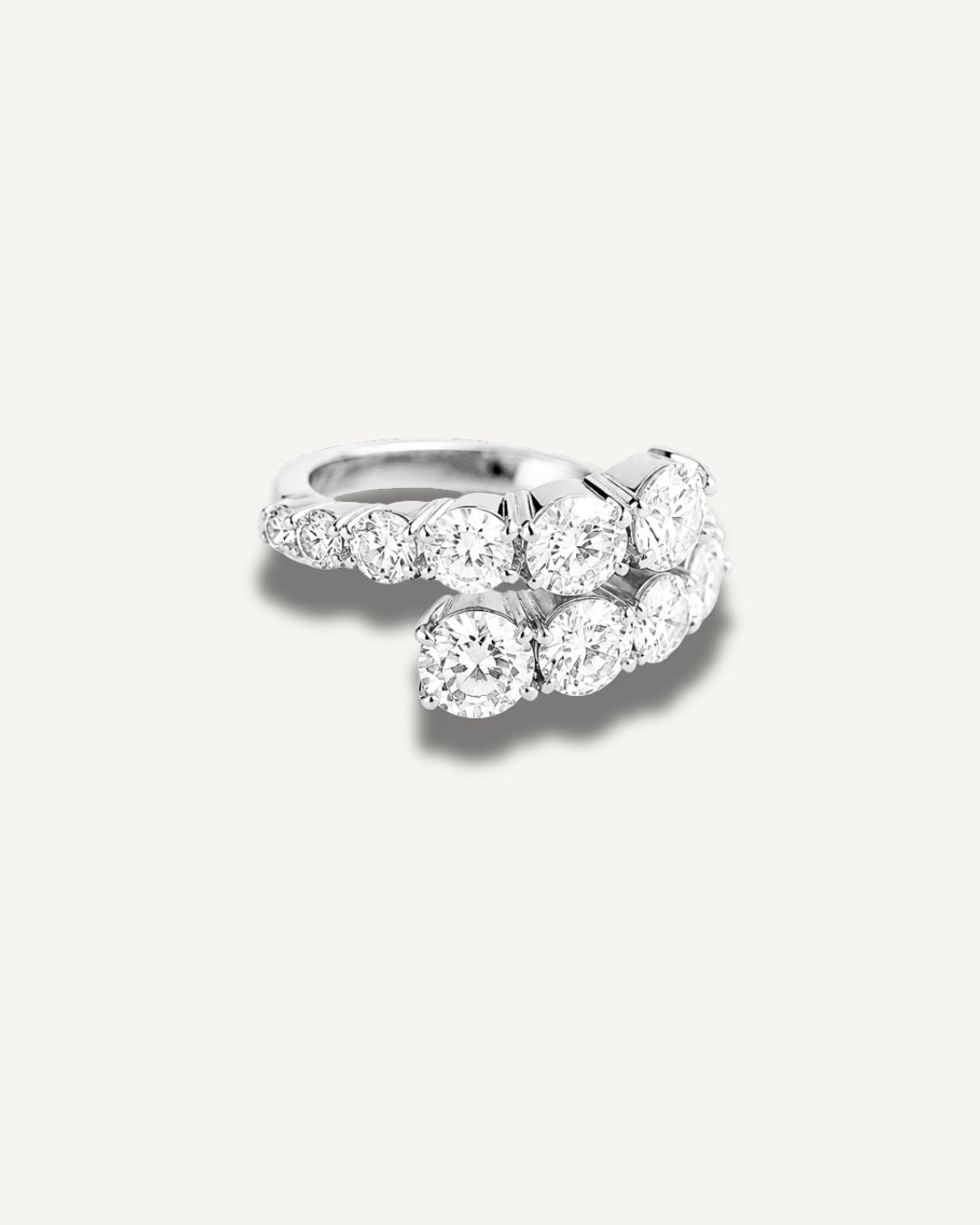 A silver-toned wrap ring featuring graduated round-cut moissanite in a curved, layered cluster design, photographed on a clean off-white background.