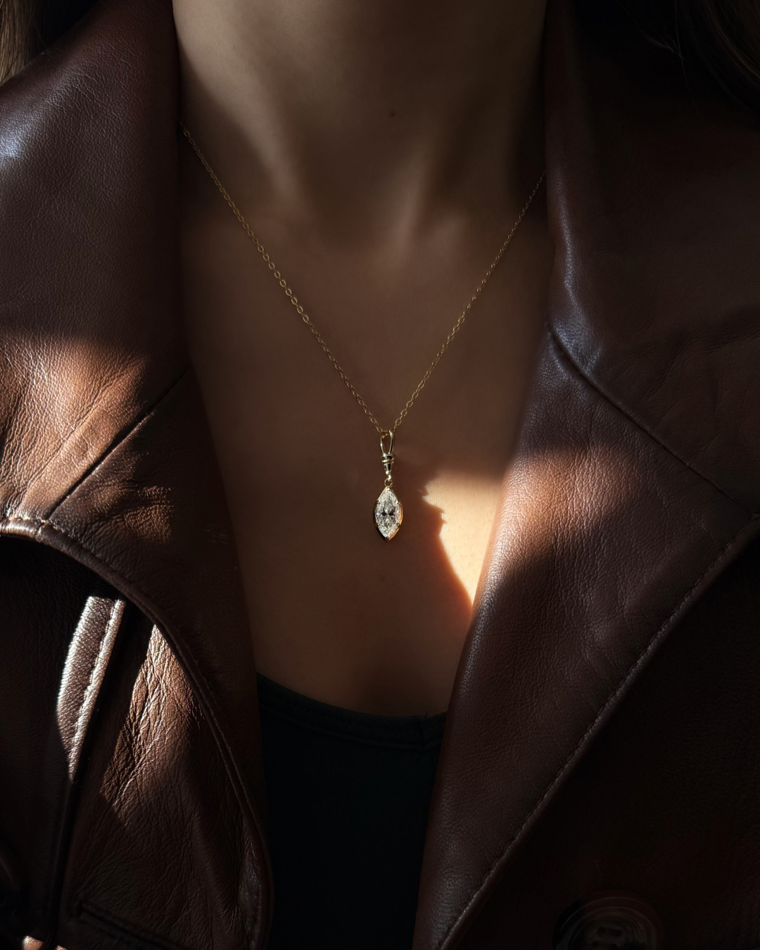 Editorial style image of marquise white moissanite necklace styled with leather jacket for modern romance look by Kampy